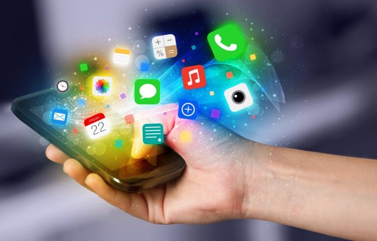 Dłoń z telefonem, z którego wyłaniają się ikony aplikacji