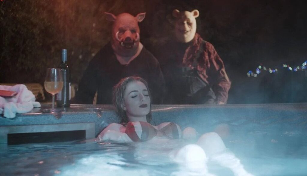 Kadr z horroru Winnie the Pooh: Blood and Honey z dziewczyną w jacuzzi, za którą stoją Puchatek i Prosiaczek