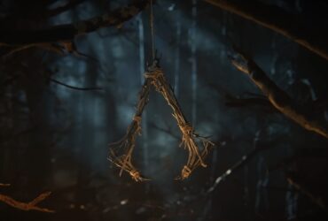 Wiszące na drzewie, zrobione z gałęzi logo serii AC z teasera Assassin's Creed Codename HEXE