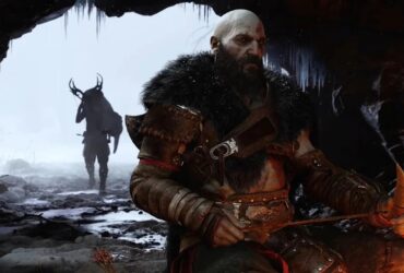 Kratos z futrem na ramionach siedzący w jaskini