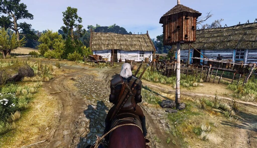 Geralt z Rivii na koniu w małej wsi w grze Wiedźmin 3: Dziki Gon.