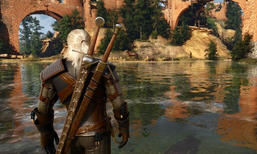 Geralt stojący nad jeziorem przy ceglanym moście w grze Wiedźmin 3: Dziki Gon