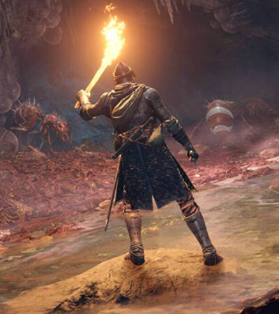 Gracz Elden Ring przemierzający jaskinię z pochodnią w ręku