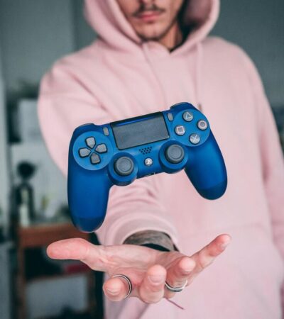 Mężczyzna podrzucający niebieski kontroler od PlayStation 4