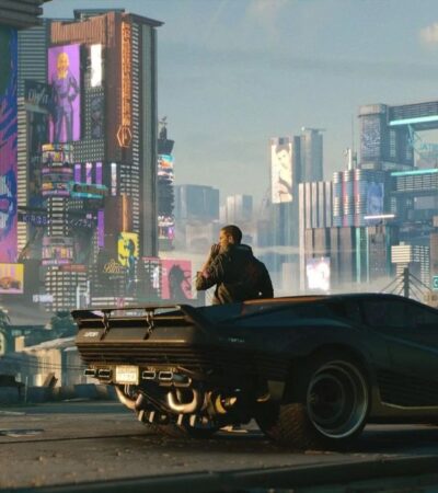 Vi opierający się o samochód przed miastem Night City w Cyberpunk 2077