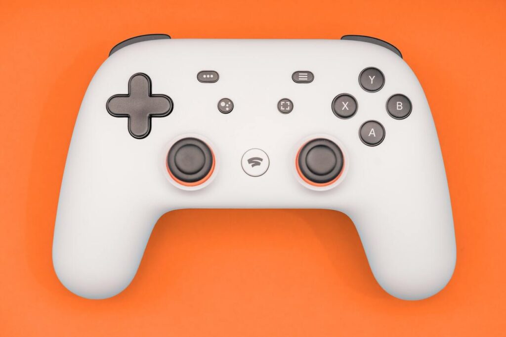 Kontroler od Google Stadia na pomarańczowym tle