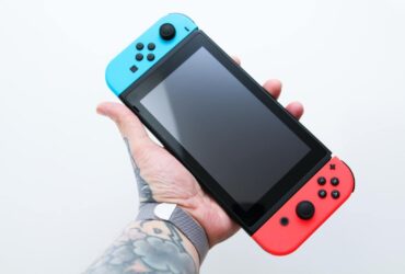 Mężczyzna z tatuażami trzymający konsolę Nintendo Switch