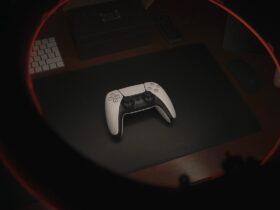 Biały kontroler od PlayStation 5 leżący na czarnym biurku