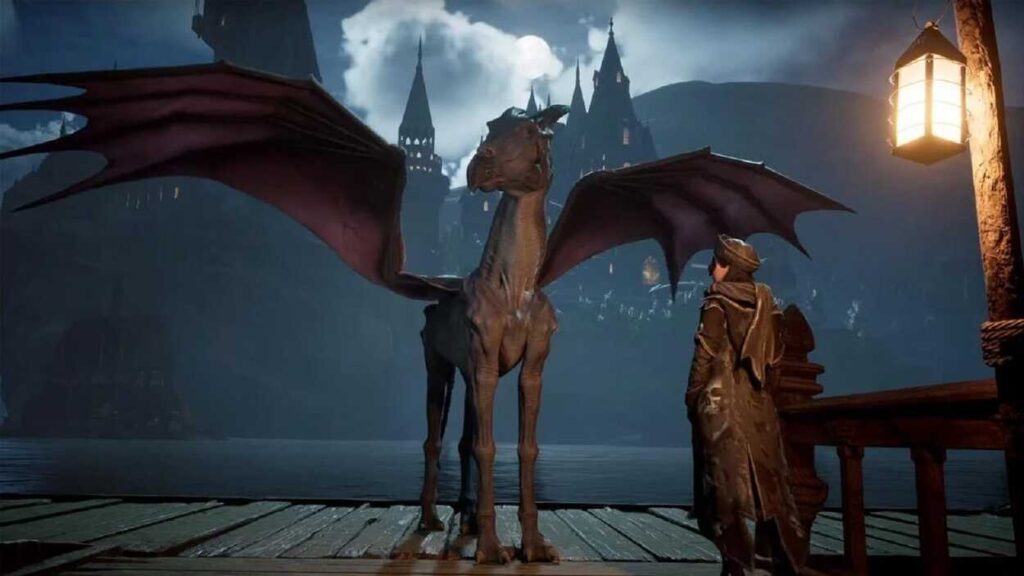 Główny bohater Hogwarts Legacy stoi obok testrala na tle Hogwartu