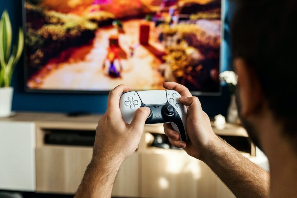 Gracz grający na PlayStation 5 za pomocą białego kontrolera