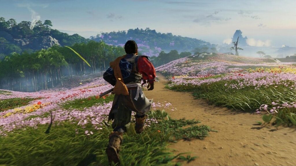 Bohater Ghost of Tsushima biegnie przez łąkę z różowymi kwiatami